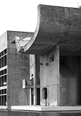 Crno-bijela fotografija betonske zgrade sa zakrivljenim krovnim elementom