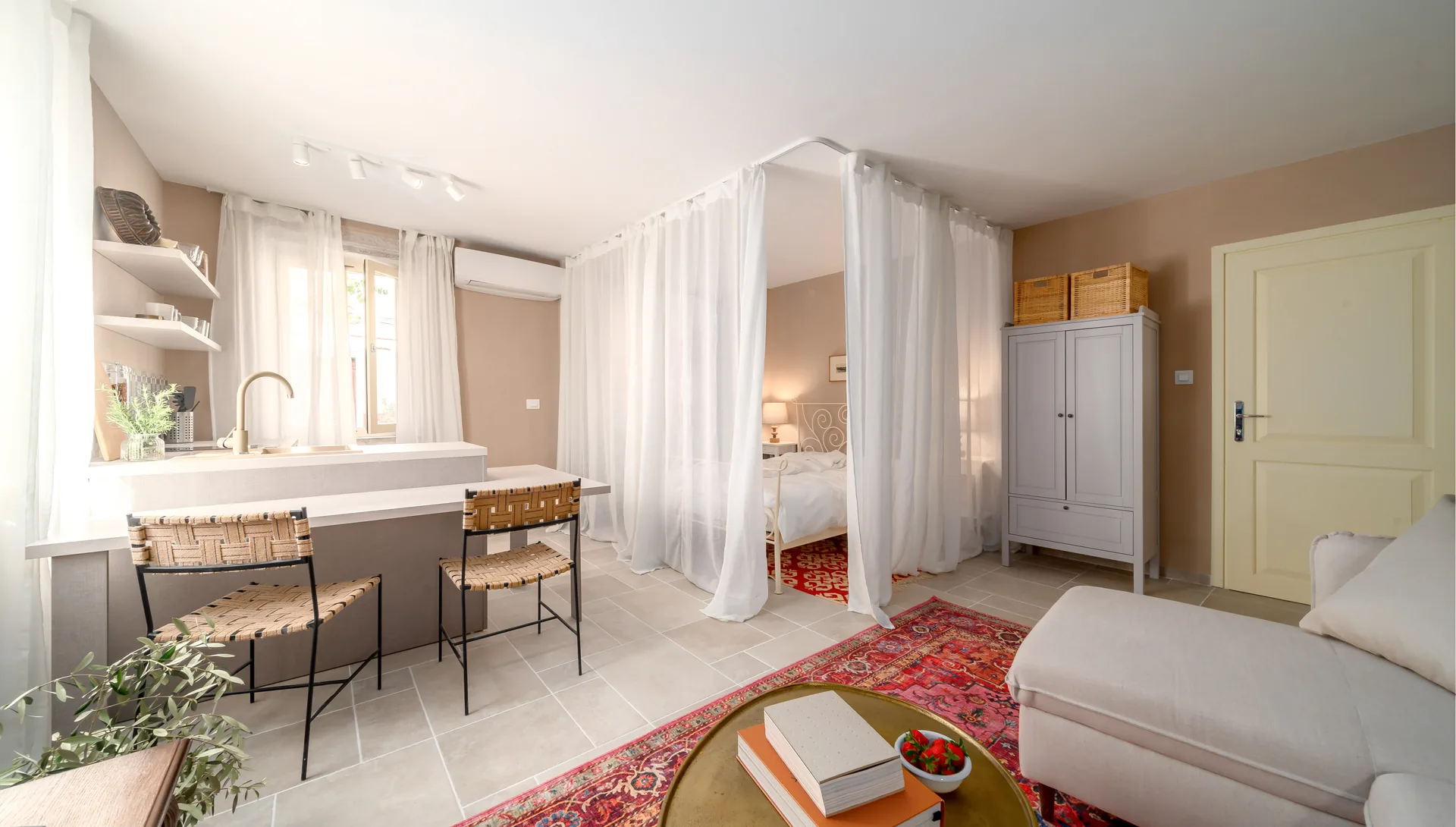 Fotografija otvorenog apartmana u Rovinju s kuhinjom, šankom i krevetom pod bijelim baldahinom