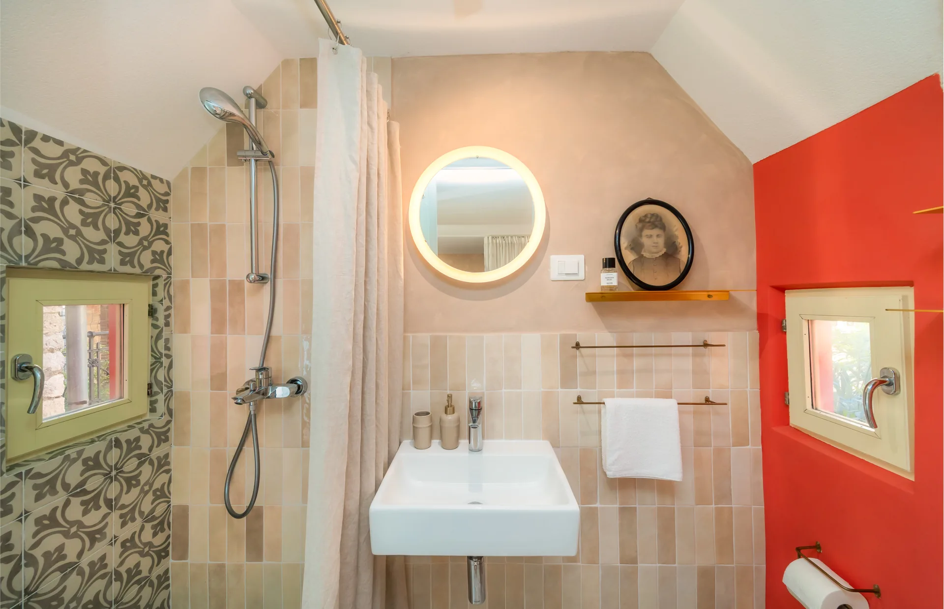 Fotografija kupaonice apartmana u Rovinju s bež pločicama, ornamentima i naglašenim crvenim zidom